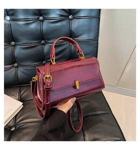 Nahaufnahme der weinroten Ölwachs-Lederhandtasche mit goldener Schnalle auf Sofa