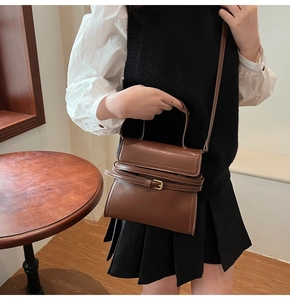Détail du sac à main en cuir marron foncé avec boucle décorative et rabat pour femme