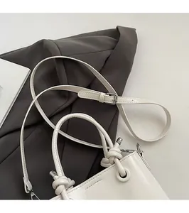 Close-up of cream white leather bucket bag with knotted handle and silver hardware