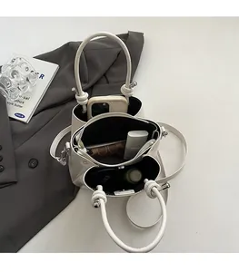 Detail view of cream bucket bag with triple compartments and unique round knotted handle
