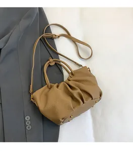 Détail de sac à main en cuir grainé avec design plissé et rivets de protection dorés