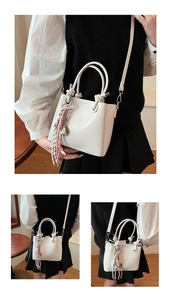 Close-up of a white leather bucket bag with knot handle and tassel charm detail