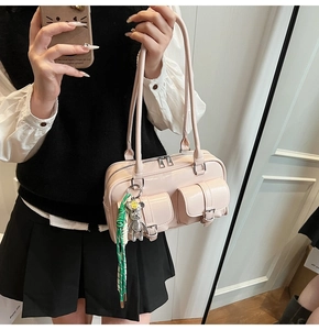Detail of light pink patent leather shoulder bag with double pockets and bear charm