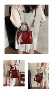 Detail of red glossy oil wax leather bucket bag with knot handle and heart charm