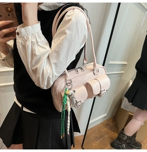 Detail of pink PU shoulder bag with cargo pockets and green braided keychain charm