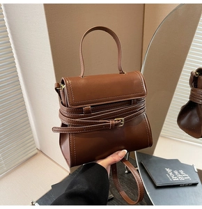 Détail d'un mini sac carré marron foncé avec boucle décorative et poignée supérieure