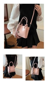 Detail of pink oil wax leather bucket bag with top handle and heart-shaped pendant charm