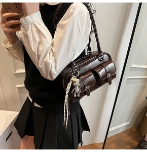 Detail of dark brown oil-wax leather shoulder bag with pockets and silver bear charm