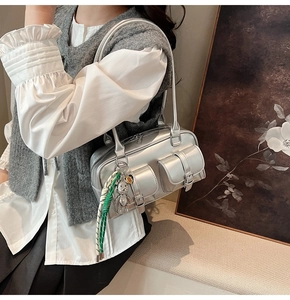 Detail of silver metallic shoulder bag with cargo pockets and rhinestone bear charm