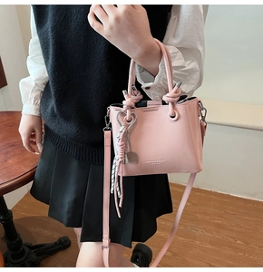 Pink retro bucket bag with knot handle and heart pendant shown in a lifestyle scene