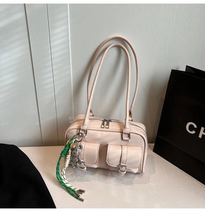 Detail of light pink patent shoulder bag with silver buckles and decorative charm
