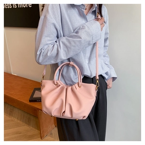 Détail d'un sac rose en cuir texturé avec design plissé et boucles en métal doré poli