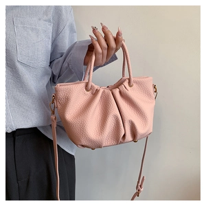 Détails de la texture d'un sac plissé rose avec finition grainée et boucles dorées