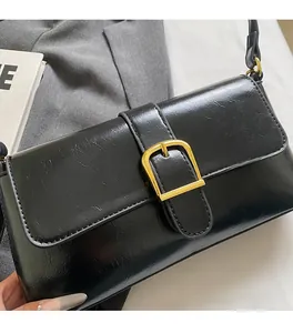 Gros plan du sac baguette en cuir PU noir brillant avec une grande boucle dorée