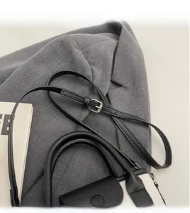 Detail of adjustable long shoulder strap on a black and white lychee leather bag