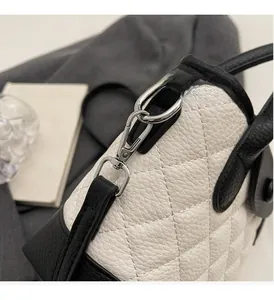 Detail of silver metal lobster clasp and black leather trim on a quilted bucket bag
