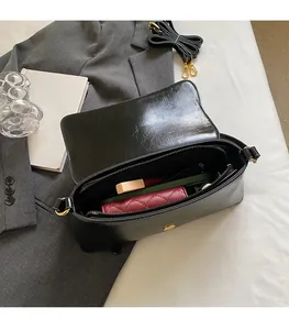 Vue intérieure du sac baguette noir montrant le rangement pour téléphone et maquillage