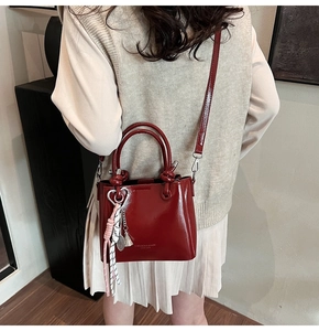 Detail of red oil wax leather bucket bag with charms and detachable shoulder strap