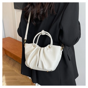 Détail d'un sac à main blanc plissé avec texture grainée et boucles dorées