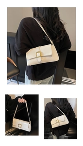 Détails du sac baguette en cuir crème avec boucle dorée et texture à grain fin