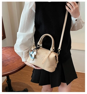 Dettaglio della borsa Boston beige con lettere in rilievo e ciondolo a forma di cavallo