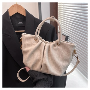 Détail du sac plissé beige montrant le cuir grainé et les finitions en bronze vintage
