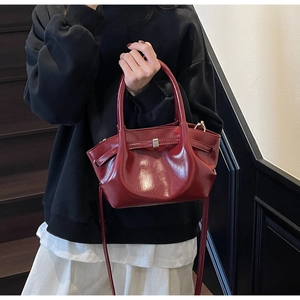 Dettaglio della borsa vintage rosso scuro con trama lucida e fibbia in metallo