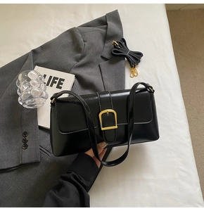 Détail du sac baguette noir avec boucle dorée et bandoulière en cuir réglable