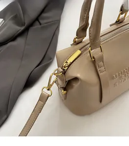Close-up of smooth gold zipper and embossed leather detail on Boston handbag
