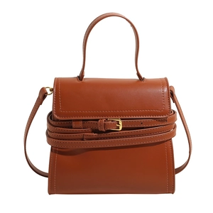 Sac bandoulière tendance en cuir marron avec poignée et boucle décorative sur fond blanc