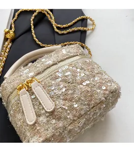 Detailed close-up of beige tweed bucket bag with sequins and golden chain strap