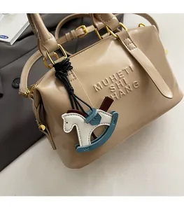 Detail of beige leather bag with gold hardware and a horse charm on grey suit jacket