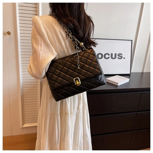 Detail of black quilted shoulder bag featuring gold twist lock and chain strap