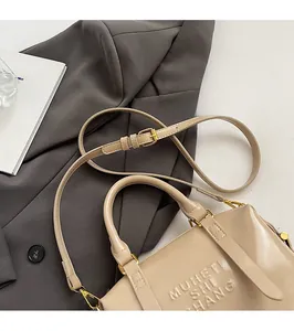 Detailed view of the embossed brand logo on a tan faux leather tote bag with gold hardware