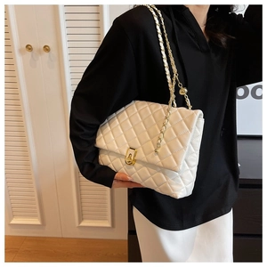 Close-up of white quilted flap bag with gold chain strap and metal ball adjuster