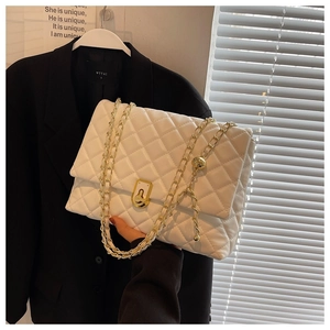 Close-up of white quilted leather bag with gold chain strap and square metal buckle