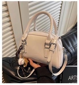 Detail of cream bowling bag with leather texture and baseball theme charm accessories