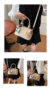 Vue détaillée d'un sac Boston beige avec lettrage embossé et pendentif cheval à bascule
