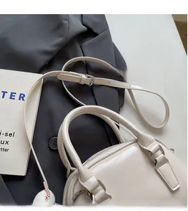 Detail of cream bowling bag showing adjustable shoulder strap and baseball pendant