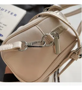 Close-up of cream white glossy leather handbag with shiny silver metal hardware and zipper
