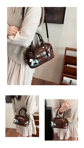 Détail du sac Boston en cuir brillant marron foncé avec logo embossé et breloque poney
