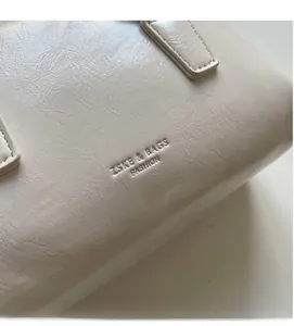 Macro view of creamy white oil-wax leather texture with embossed ZSKE & BAGS logo
