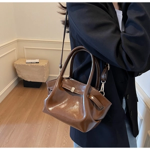 Dettaglio della borsa tote marrone lucida con silhouette alata e trama in pelle fine
