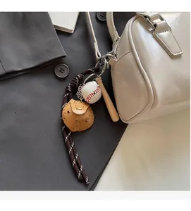 Close-up of baseball keychain with mini bat and glove on a beige handbag