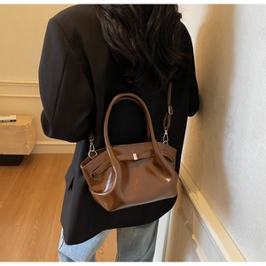 Dettaglio borsa tote marrone scuro lucida con design a pieghe e chiusura in metallo