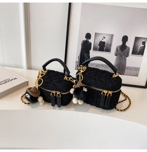 Detail of black tweed mini bag with gold chain strap and cute plush charm detail