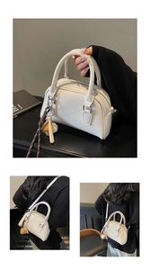 Detail of off-white bowling bag with dual handles, zip closure and baseball charm