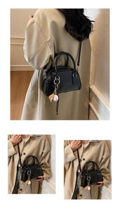Detail view of a black glossy bowling bag with adjustable strap and cute decorative charms