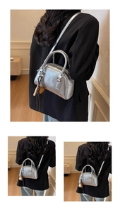 Detail of silver metallic bowling bag with top handles and adjustable crossbody strap