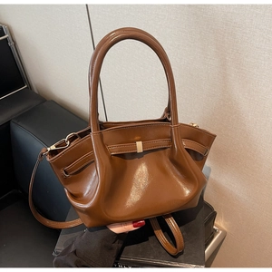 Dettaglio della borsa vintage in pelle lucida marrone con pieghe e fibbia dorata